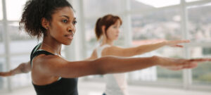 two women standing in warrior pose in a yoga class