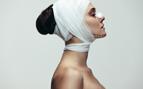 woman's face and nose bandaged after surgery