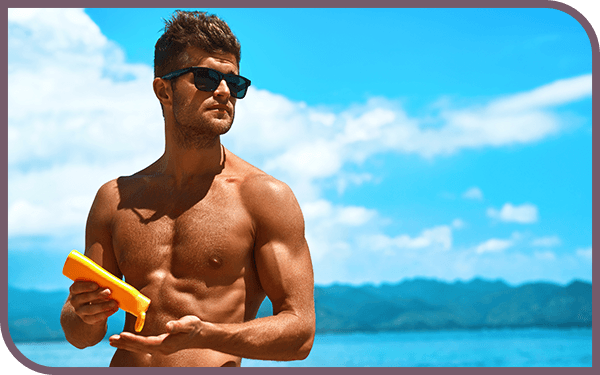 Image of a man on a beach putting on sunscreen
