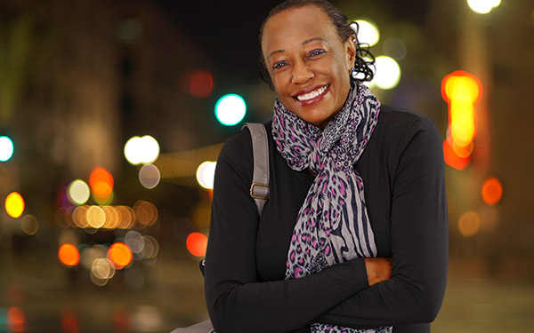 woman with a scarf smiling with arms crossed while standing outside in cold weather