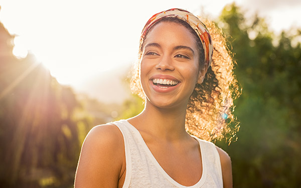 woman with a headscarf smiling outside in the sunlight