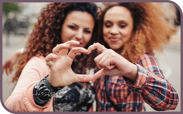 two women making a heart with their hands