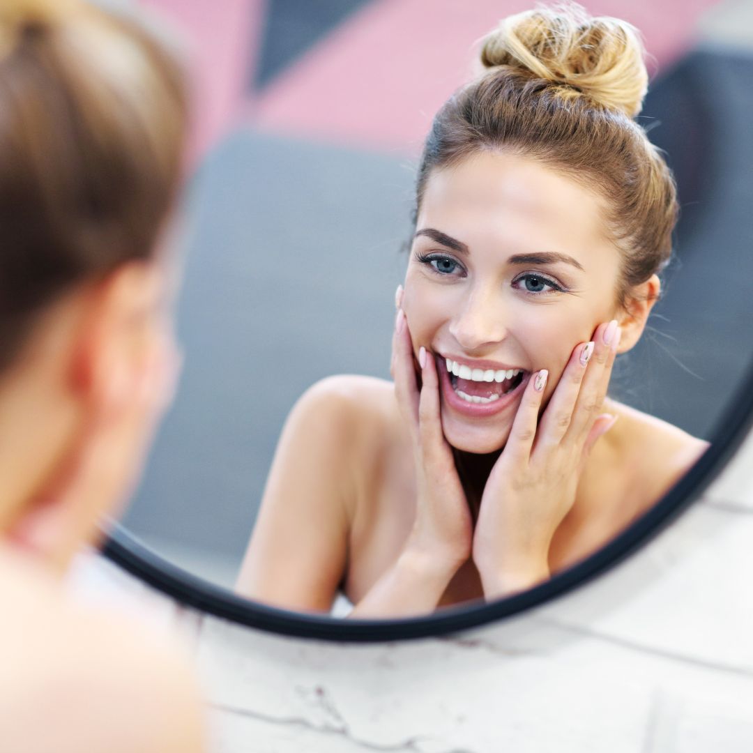 woman staring in mirror happy