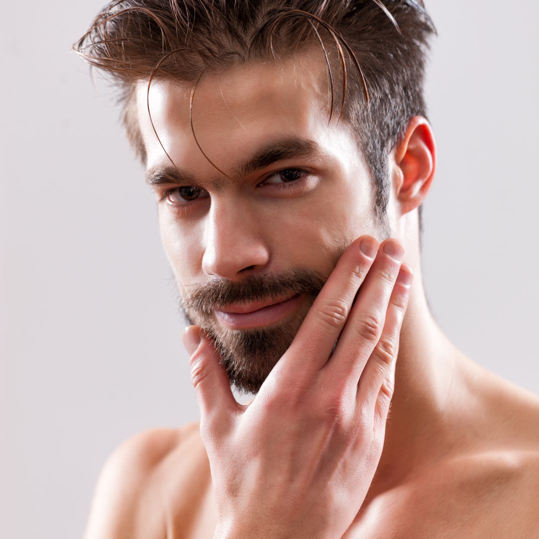 a man smiling while holding his face