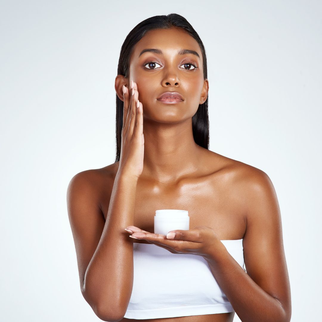 a woman applying a cream to her cheeks