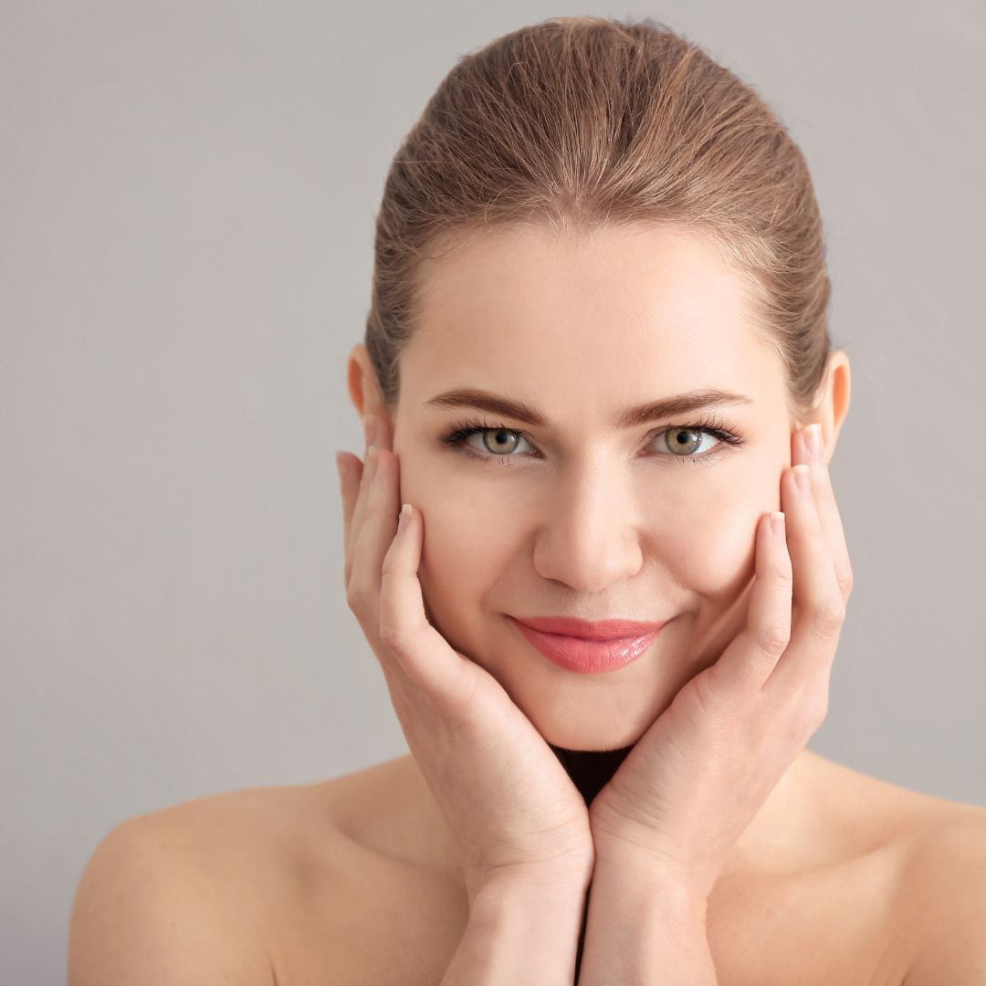 a woman smiling and touching her skin
