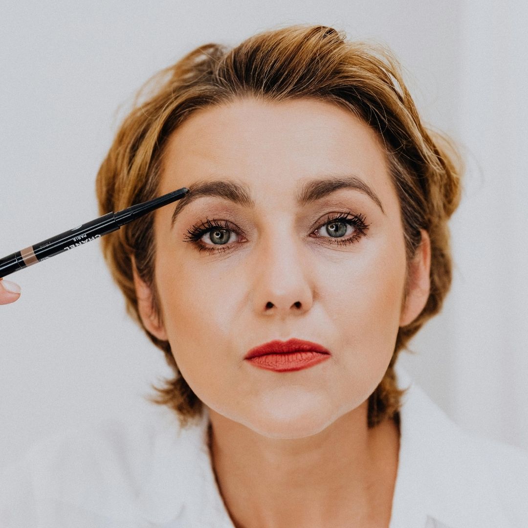 A woman applying eyebrow makeup.