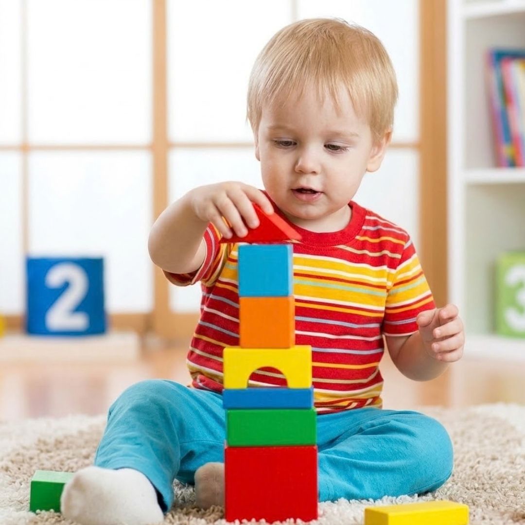 Toddler playing with a stack of colorful toy blocks.